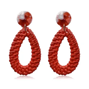 Macro detail of red woven raffia teardrop earrings with marble resin studs