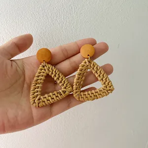 Close-up of bohemian triangle woven earrings held by hand showing actual size and texture