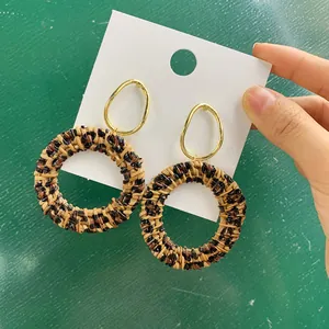 Macro-opname van luipaardprint rotan oorbellen met een gouden metalen verbindingsring