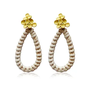 Detail of yellow floral accents and teardrop-shaped woven straw earrings in boho style