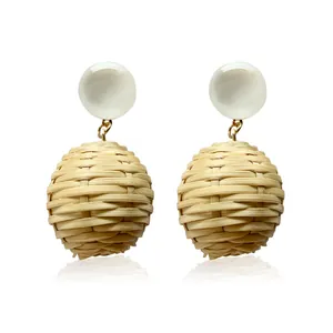 Detail of bohemian rattan ball drop earrings with white resin studs and gold links