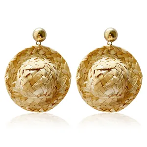 Detailed macro view of woven straw hat pendant earring with polished golden metal stud