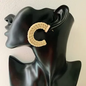 Handmade bohemian rattan woven C-shaped hoop earrings on a black fashion model