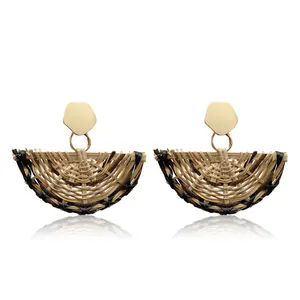 Detailed macro view of woven rattan fan-shaped earrings with gold geometric metal studs