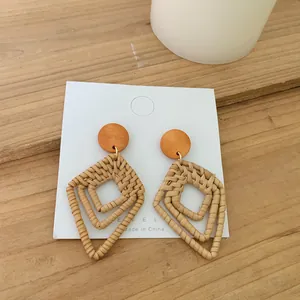 Handmade bohemian rattan earrings with geometric wooden studs on a white display card