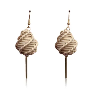 Macro view of geometric rattan weave and gold-plated metal drop earrings texture