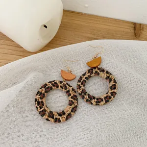 Macro shot of handmade leopard print rattan earrings on textured white fabric