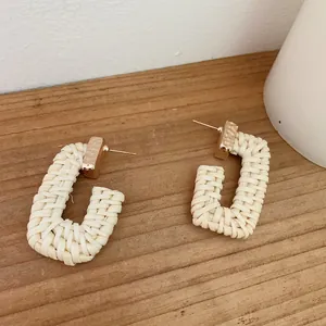 Detail of cream woven U-shaped earrings with hammered gold metal accents for women