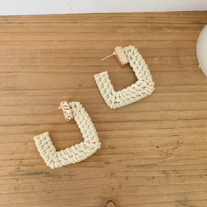 Detail of square raffia woven earrings with hammered gold metal texture accents