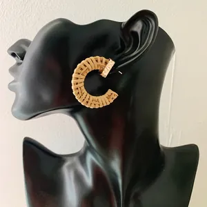 Handmade woven C-shaped rattan hoop earrings with gold metal studs on mannequin