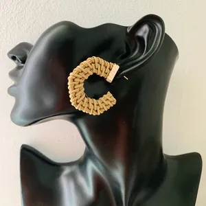 Bohemian C-shaped geometric rattan drop earrings with gold metal clasp on a model
