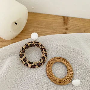 Detailed macro shot of large round hand-woven rattan earrings with leopard print accents