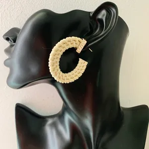 Close-up of Bohemian cream-colored woven C-shape rattan earrings on a model display