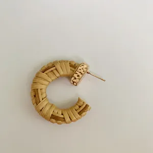 Detailed macro view of woven raffia texture on C-shaped earring with golden metal piece