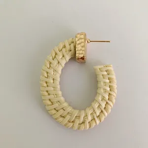 Macro detail of Bohemian C-shape earrings featuring hand-woven fiber and hammered gold metal
