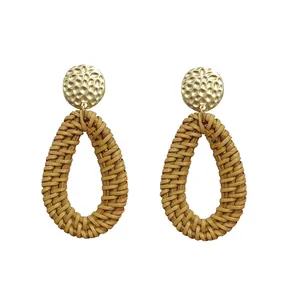 Detailed view of bohemian teardrop rattan earrings with gold hammered metal accents