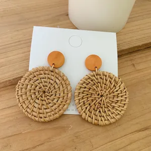 Macro detail of Bohemian round woven rattan earrings on a wooden textured background