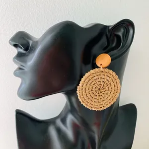 Detail of bohemian round woven rattan earrings on a black mannequin display