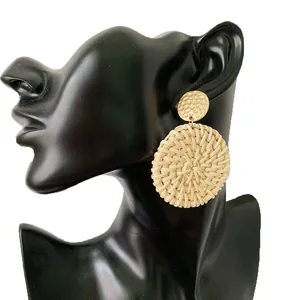 Close-up of bohemian woven rattan earrings featuring a hammered gold metal stud design