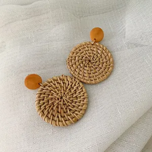 Detail of handmade round woven rattan earrings with natural wood stud and straw texture