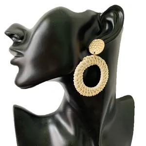 Detail of bohemian rattan drop earrings with hammered gold metal studs on a model
