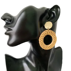 Bohemian rattan drop earrings with hammered gold metal studs on a model display