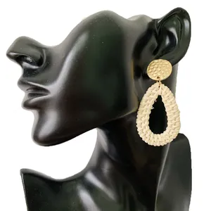 Detailed shot of bohemian drop earrings featuring woven ivory rope and hammered gold discs