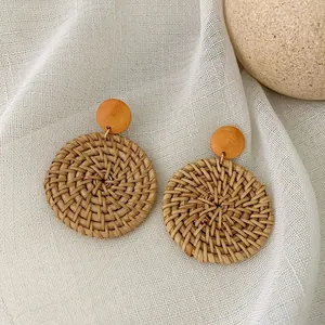 Detail of round handmade rattan woven earrings with wood studs and natural fiber texture