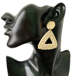 Detail of bohemian rattan earrings with triangle weave and hammered gold metal disc