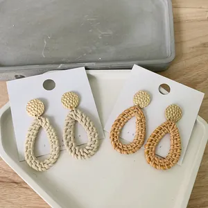 Close-up of bohemian woven rattan teardrop earrings in cream and brown on a jewelry card