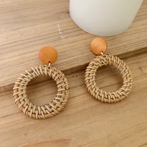 Macro shot of boho round wicker earrings with natural fiber weave and wooden stud detail