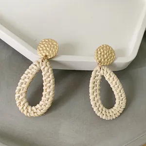 Macro detail of bohemian teardrop woven rattan earrings with textured gold metal studs