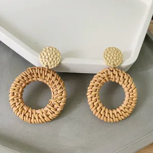 Detail of woven rattan hoop earrings with hammered gold studs on a geometric tray