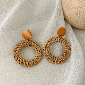 Detail of bohemian round rattan woven earrings with textured natural wood studs