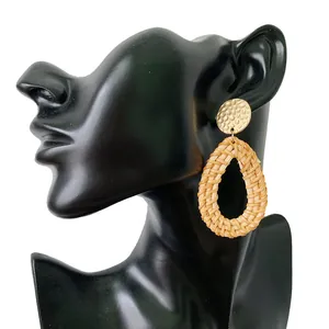 Bohemian rattan teardrop earrings with hammered gold metal studs on a display