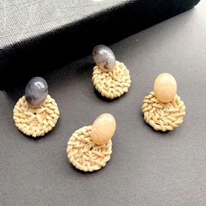Detail van gevlochten rotan oorbellen met marmeren hars kralen in grijs en beige