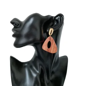 Detalle de pendientes geométricos de madera con tachuelas de concha doradas