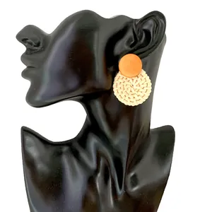 Detail of handmade bohemian woven straw drop earrings on a black display model