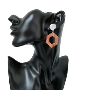Primer plano de pendientes geométricos de madera con botón blanco y colgante hexagonal marrón