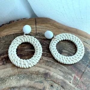 Bohemian handmade woven hoop earrings with white beads on a natural wood background