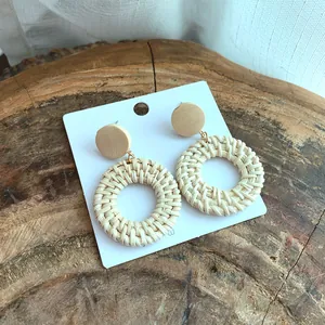 Handmade bohemian woven rattan hoop earrings with natural wooden studs on rustic wood background