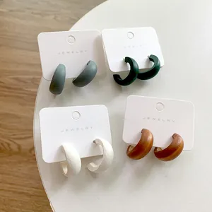 Set of four C-shaped geometric matte earrings in blue, green, white, and wood finish