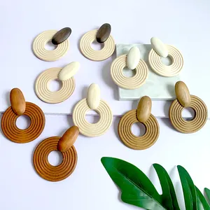Macro shot of geometric wooden hoop earrings in earthy tones on marble surface