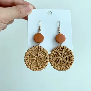 Macro view of handmade bohemian straw woven earrings with rust red round stud details