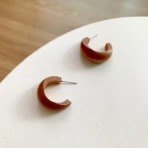 Retro C-shaped wooden hoop earrings with silver pins on a minimalist white display