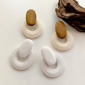 Detailed view of geometric spiral wooden earrings with layered circular pendants on a beige base