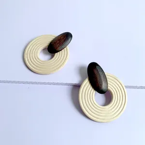 Detailed macro view of geometric round wooden earrings with ripple texture and dark wood accents