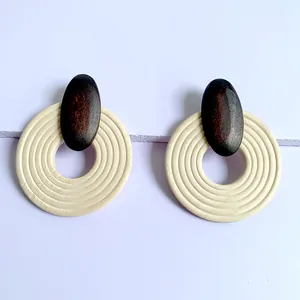 Close-up of cream white large round wooden earrings with concentric circular grooves
