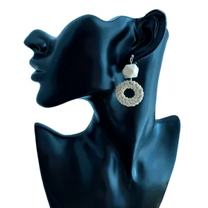 Detail of bohemian handmade straw woven hoop earring with geometric bead on a model