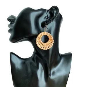 Handmade woven rattan hoop earrings in bohemian style on black jewelry display stand